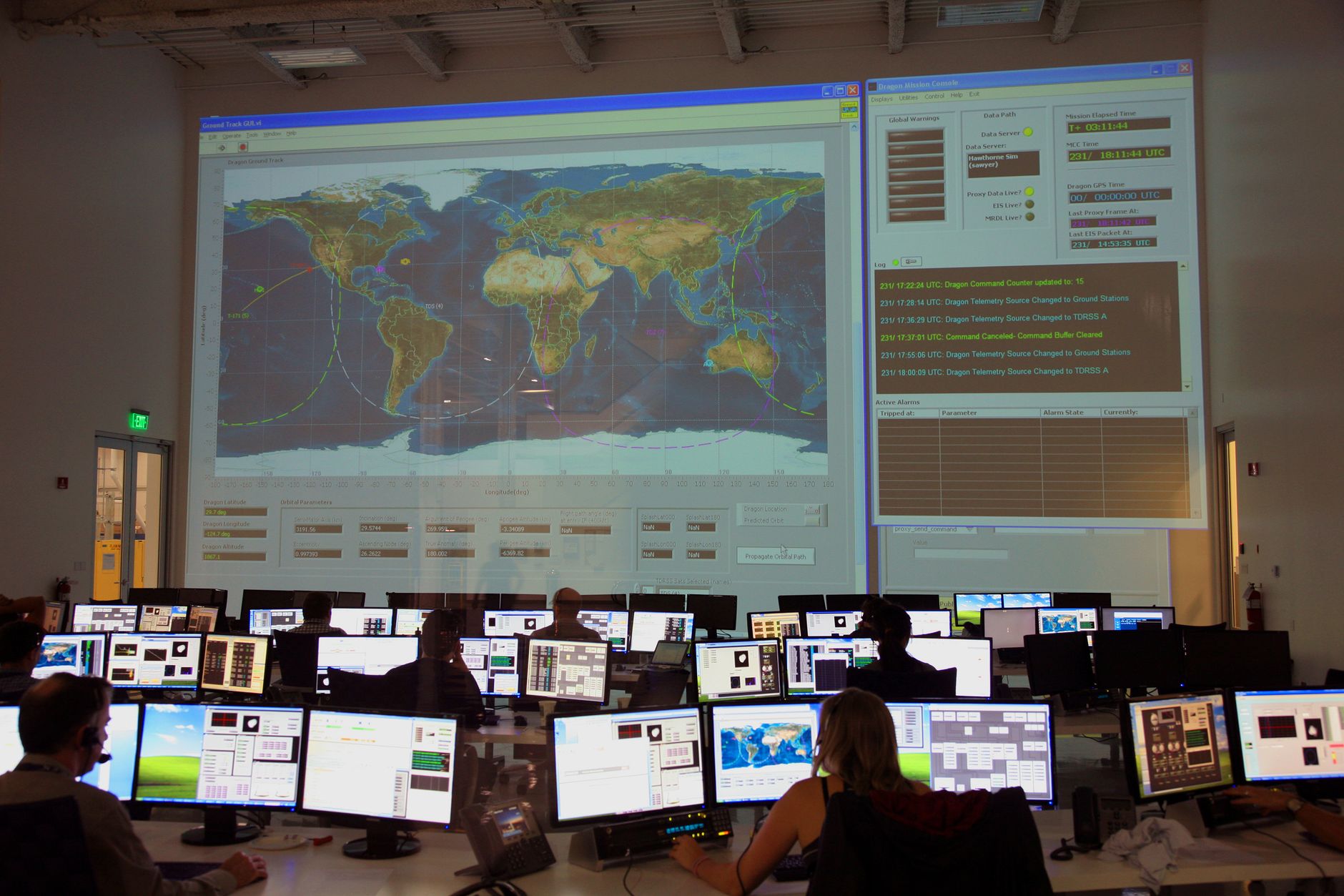 Analysts in a control room facing a large world map